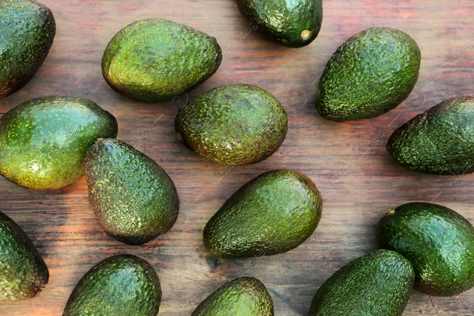 Photo of Many tasty ripe avocados on wooden table, top view