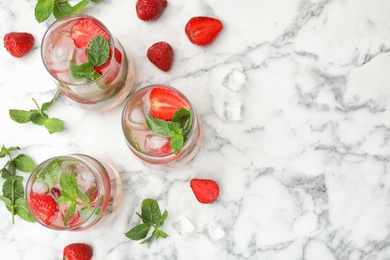 Photo of Glasses of refreshing drink with strawberry and mint on marble table, flat lay. Space for text