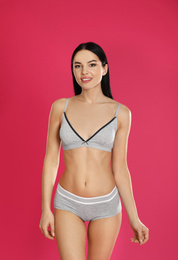 Photo of Beautiful young woman in grey sportive underwear on pink background