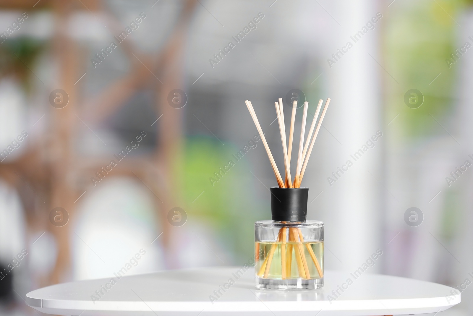 Photo of Aromatic reed air freshener on table against blurred background