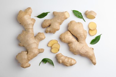 Photo of Fresh ginger with green leaves on white background, flat lay