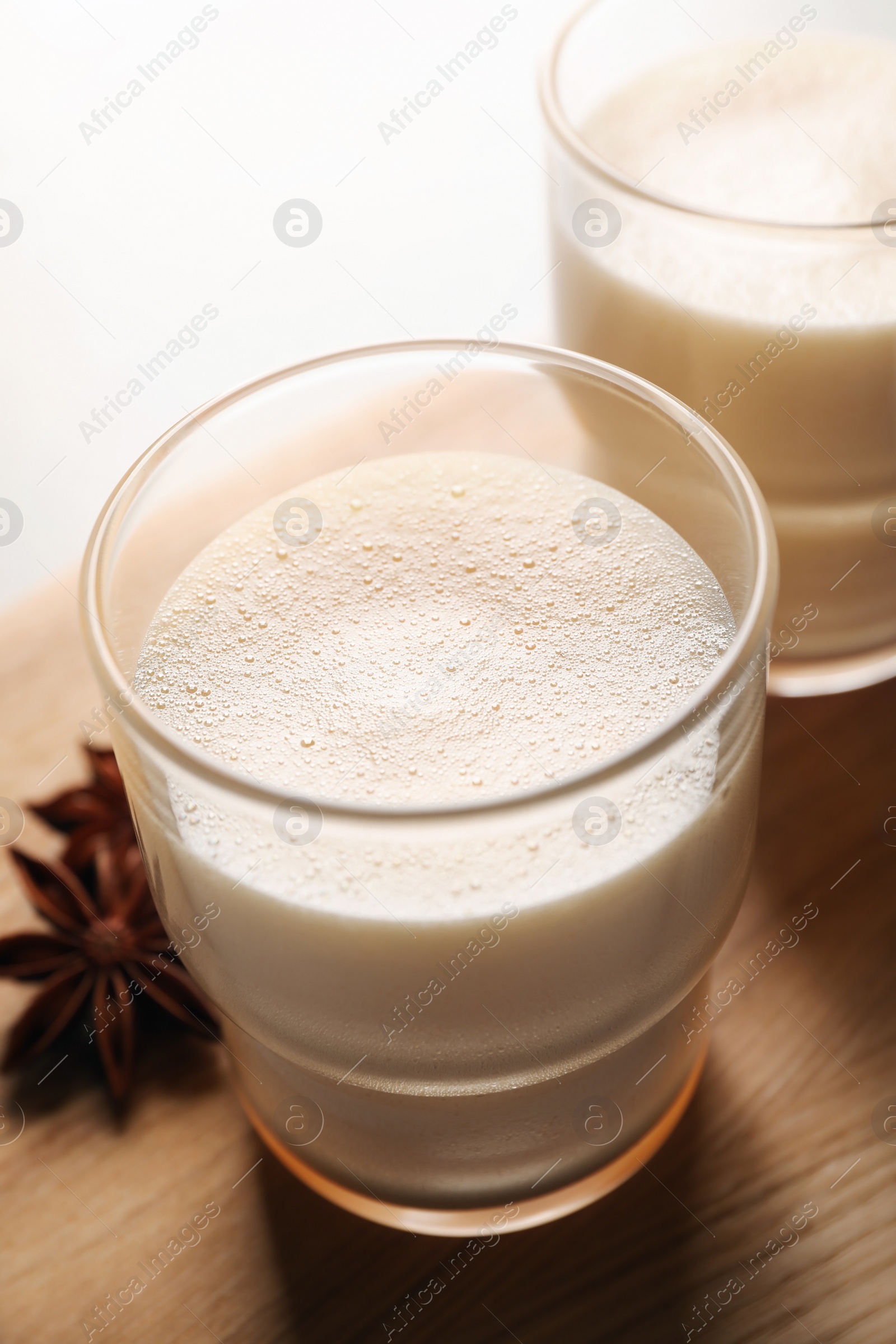 Photo of Glasses of delicious eggnog with anise on table, closeup