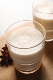 Photo of Glasses of delicious eggnog with anise on table, closeup