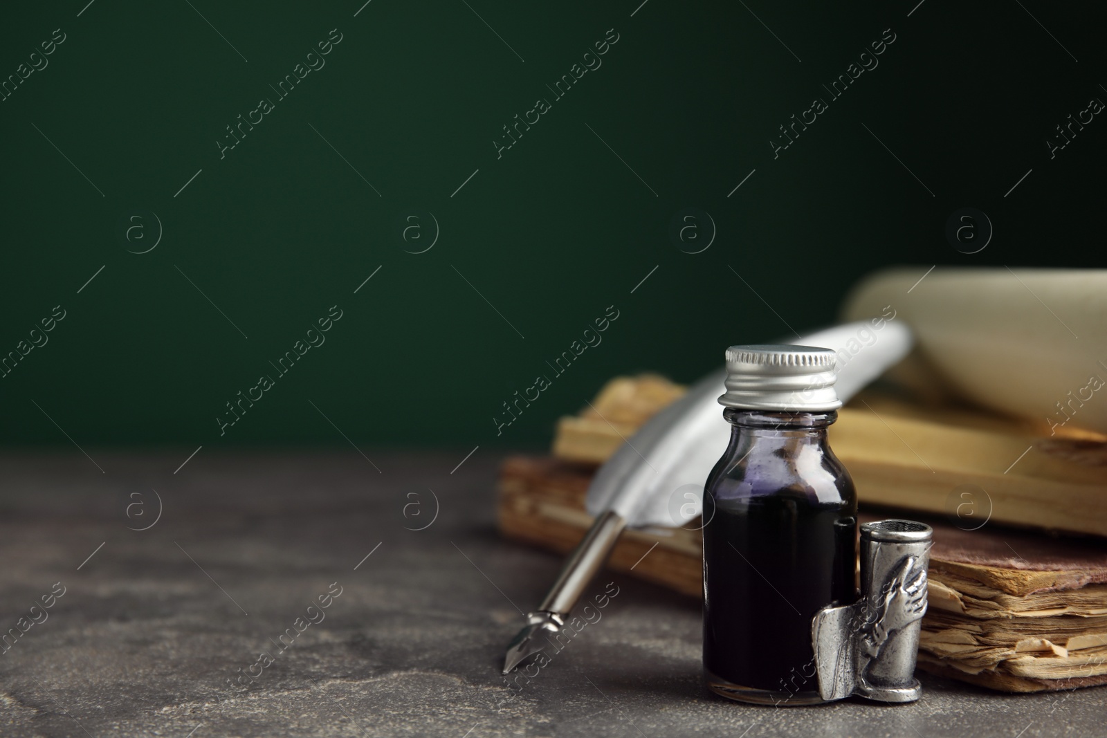 Photo of Composition with feather pen and bottle of ink on grey table. Space for text