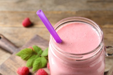 Image of Yummy raspberry smoothie in mason jar on wooden table, closeup