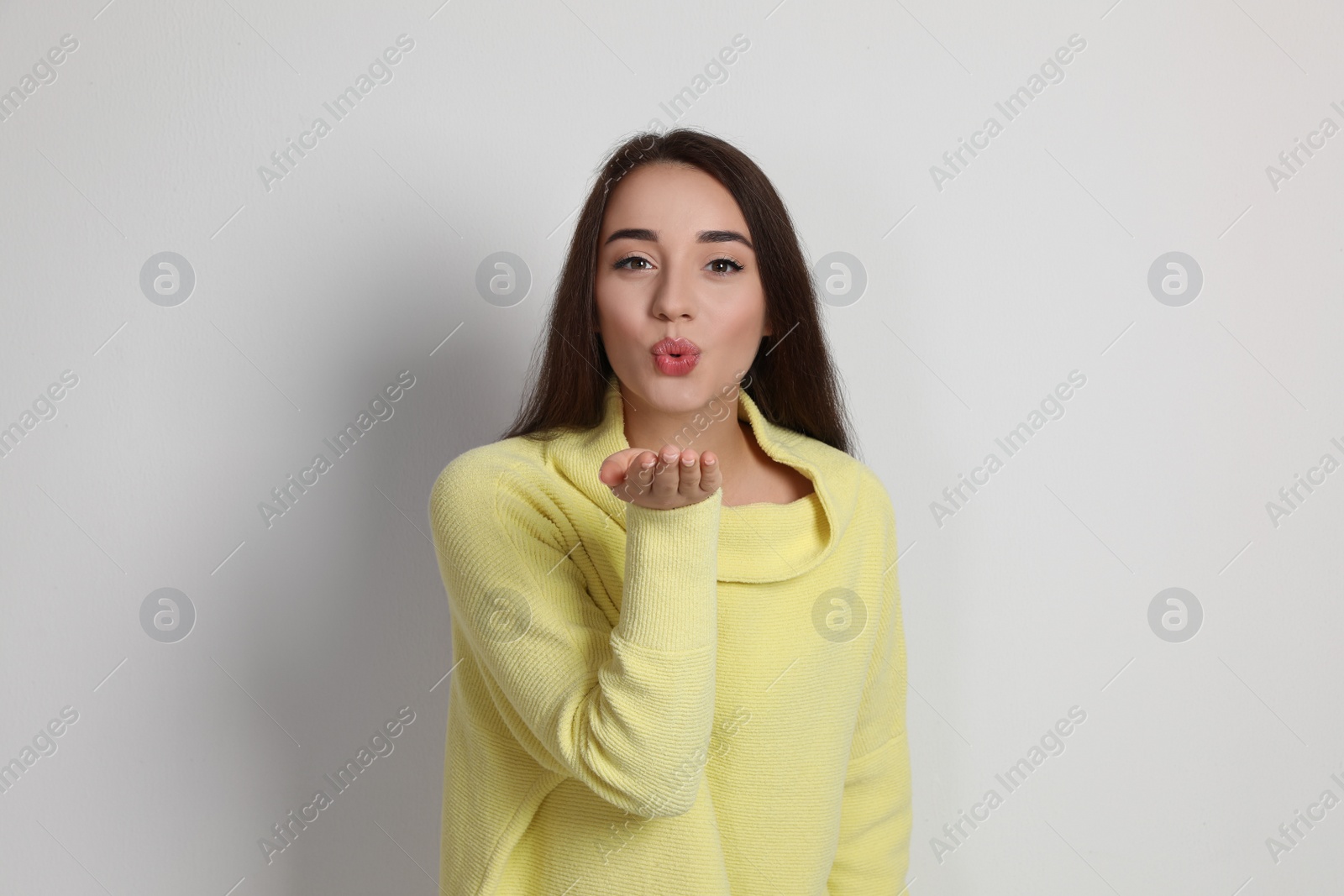Photo of Beautiful young woman wearing yellow warm sweater on white background