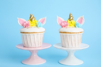 Photo of Cute sweet unicorn cupcakes on light blue background