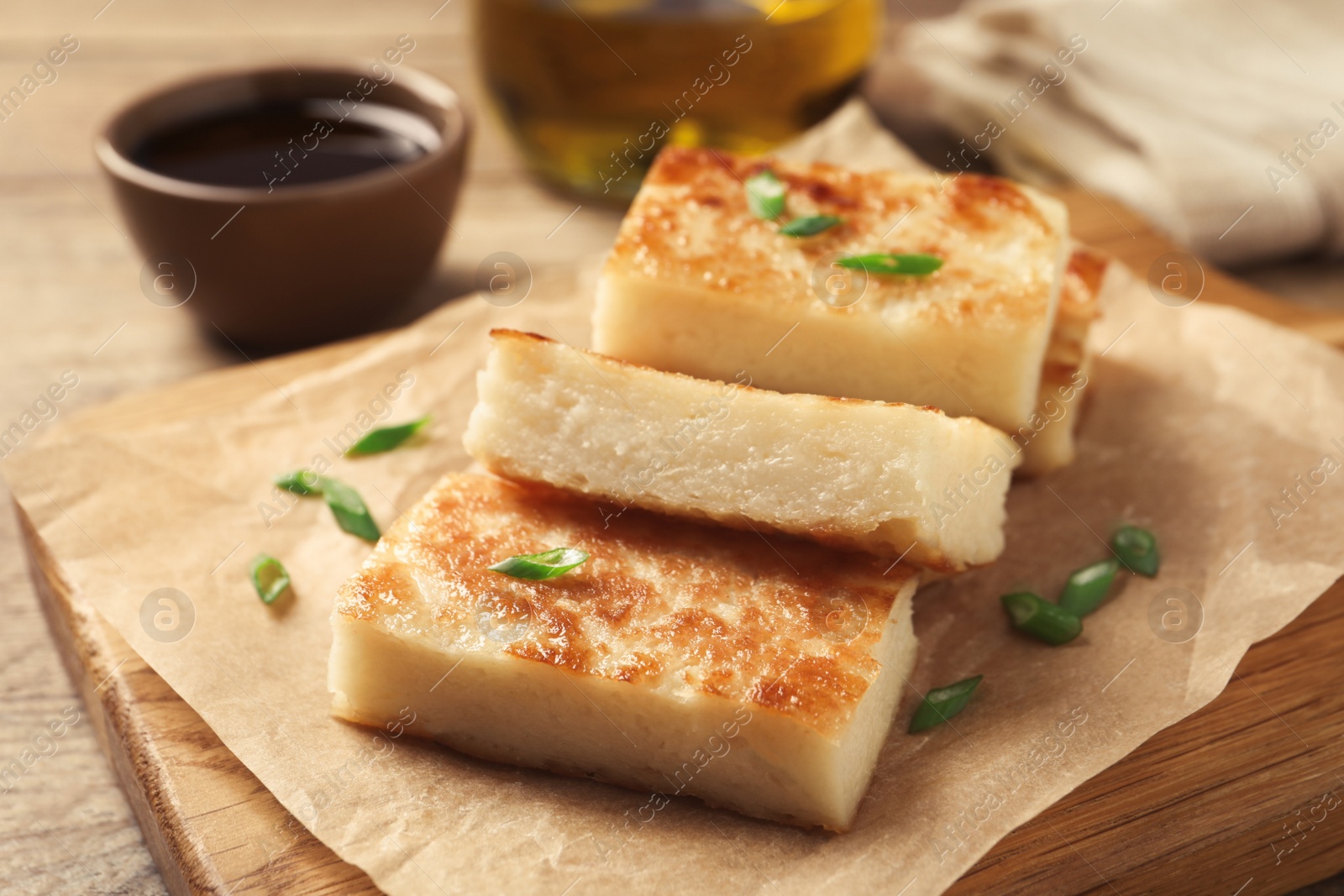 Photo of Delicious turnip cake with green onion on wooden board, closeup