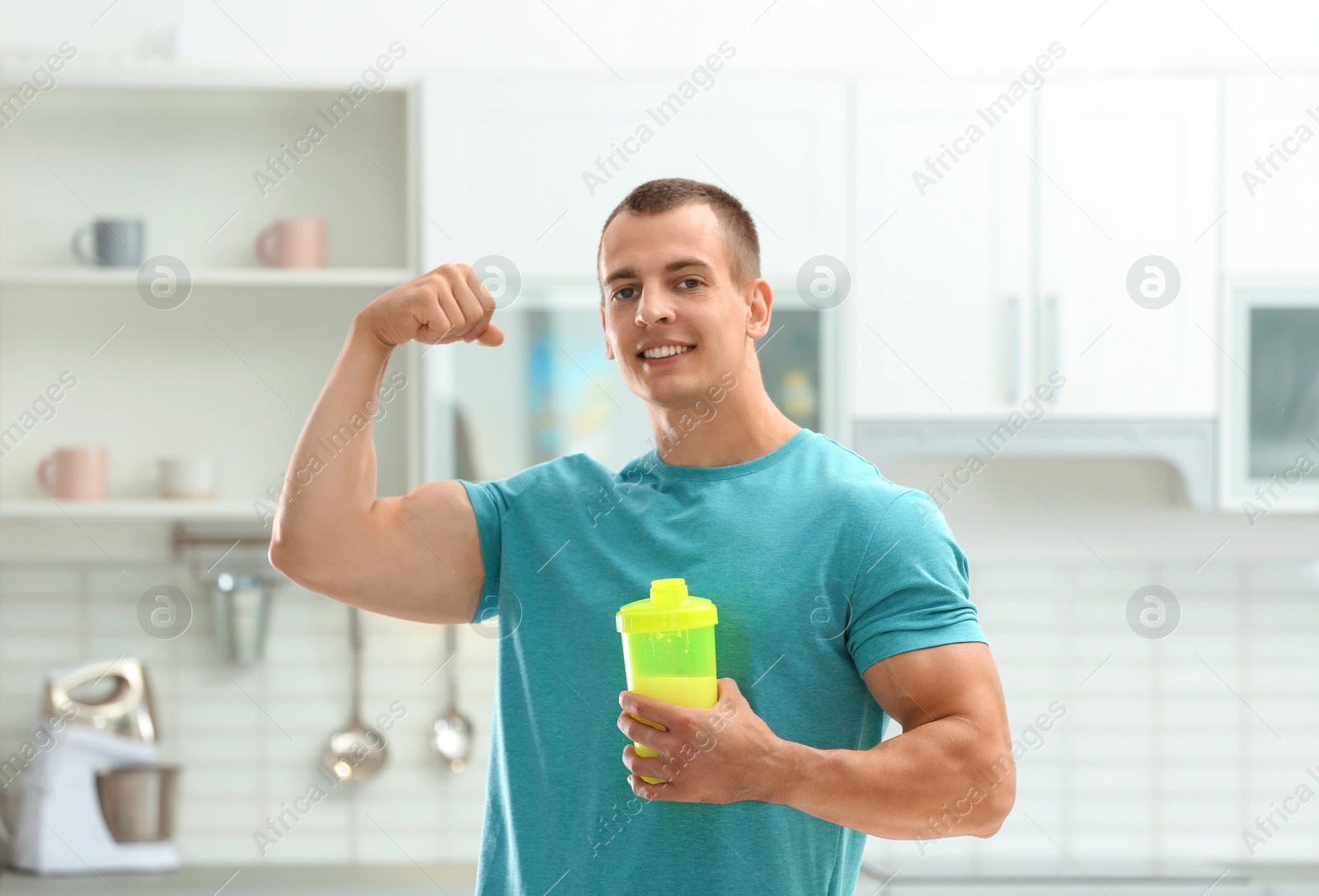 Photo of Athletic young man with protein shake in kitchen