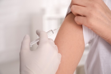 Photo of Doctor vaccinating woman against Covid-19 in clinic, closeup