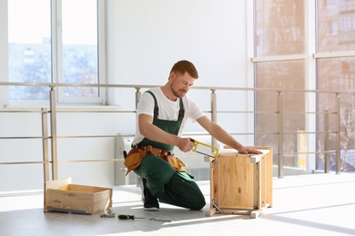 Photo of Carpenter in uniform making furniture indoors. Professional construction tools