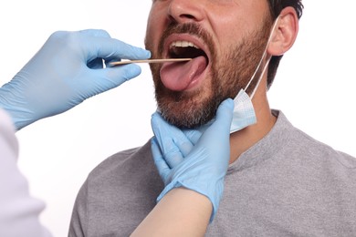 Photo of Doctor examining man`s oral cavity with tongue depressor on white background, closeup