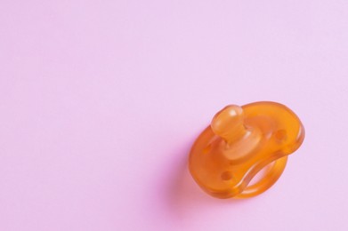 Photo of New baby pacifier on pink background, top view. Space for text