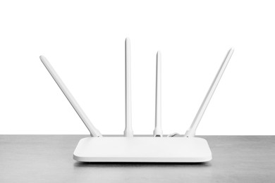 Photo of New modern Wi-Fi router on grey table against white background