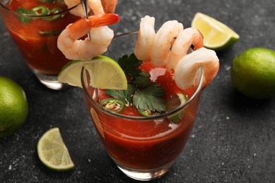 Photo of Tasty shrimp cocktail with sauce in glasses and limes on grey textured table, closeup