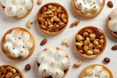 Many different tartlets on white wooden table, flat lay. Delicious dessert