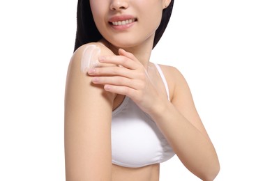 Young woman applying body cream onto shoulder on white background, closeup