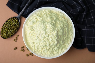 Photo of Bowl of flour, spoon and mung beans on beige background, flat lay