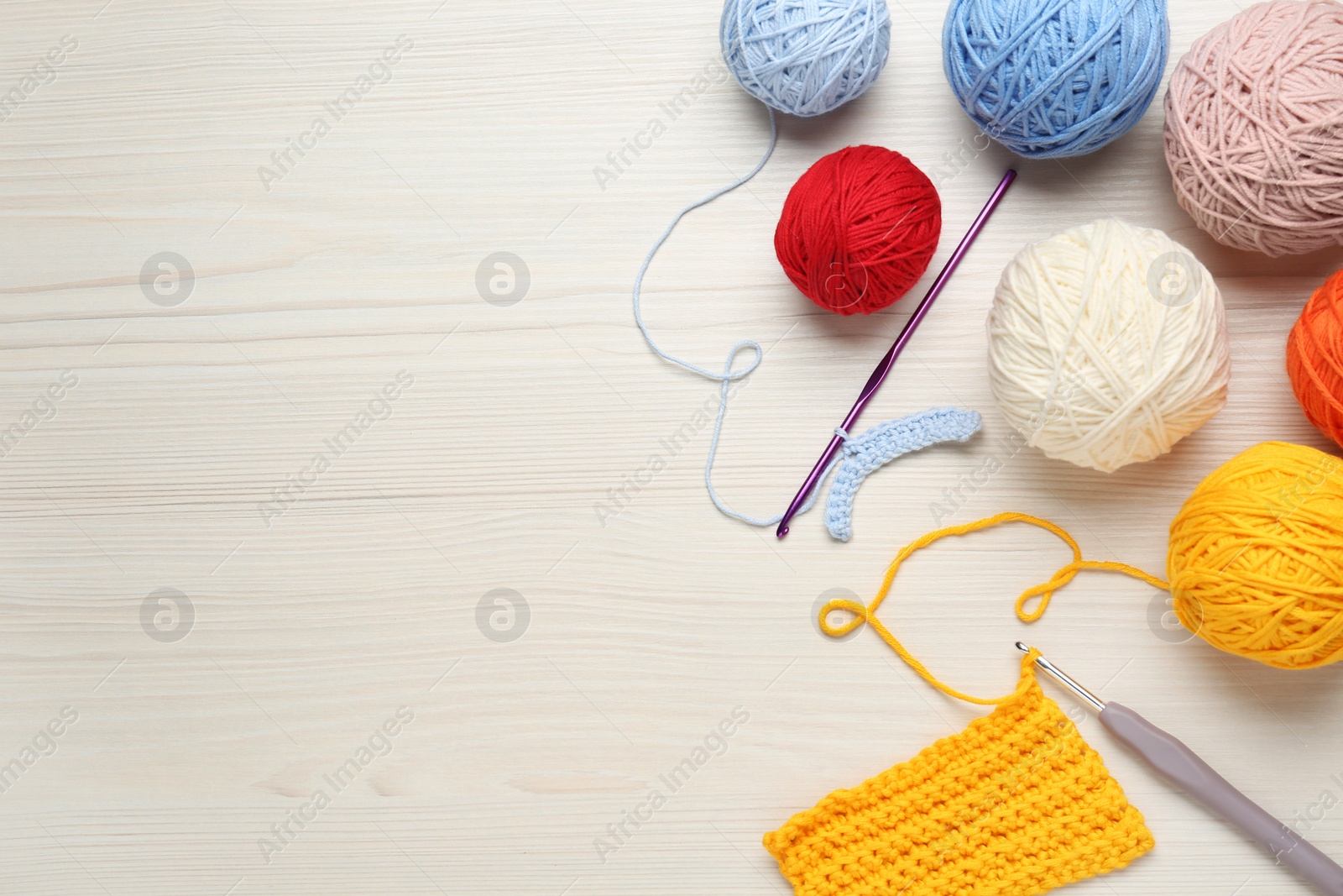 Photo of Flat lay composition with knitting threads and crochet hooks on white wooden table, space for text