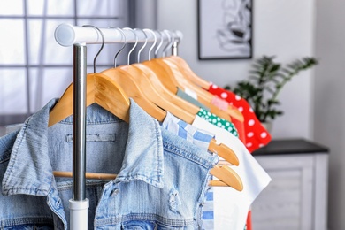 Stylish clothes hanging on wardrobe rack indoors, closeup
