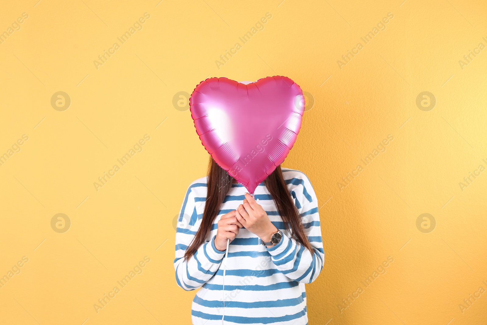 Photo of Young woman with heart shaped balloon on color background