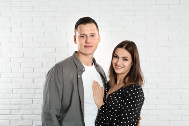 Happy young couple near white brick wall