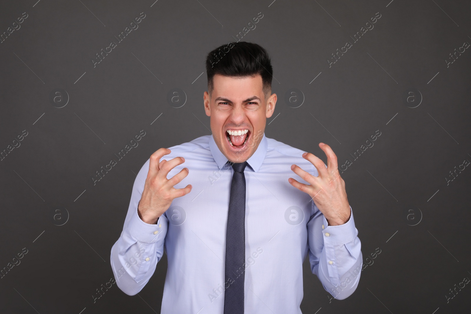 Photo of Portrait of emotional businessman on dark grey background. Personality concept