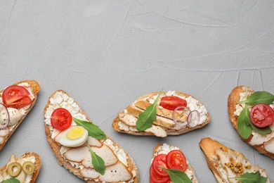 Different delicious chicken bruschettas on light grey table, flat lay. Space for text