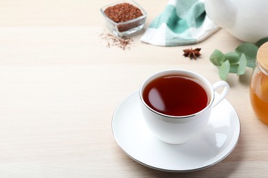 Freshly brewed rooibos tea, dry leaves and anise on white wooden table. Space for text