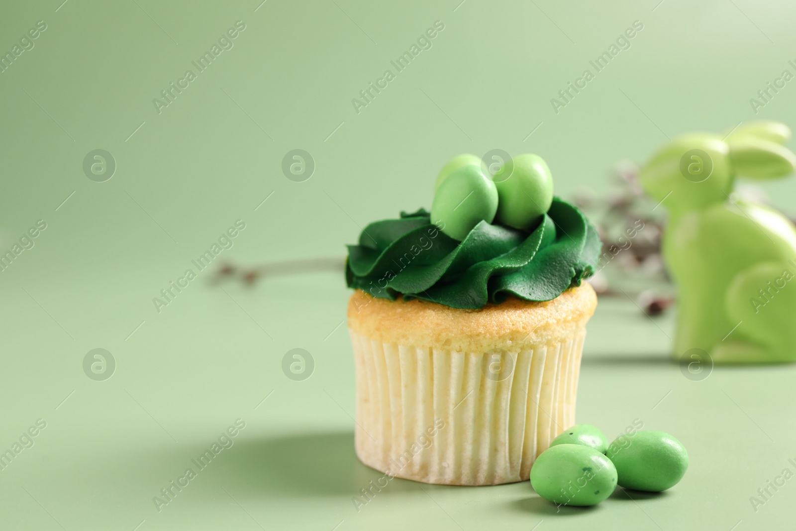 Photo of Tasty cupcake with Easter decor on green background, closeup. Space for text