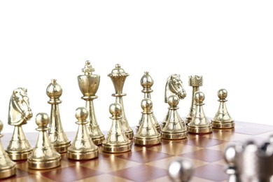 Photo of Set of golden chess pieces on wooden board against white background