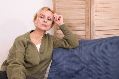 Photo of Upset middle aged woman sulking on sofa at home. Loneliness concept