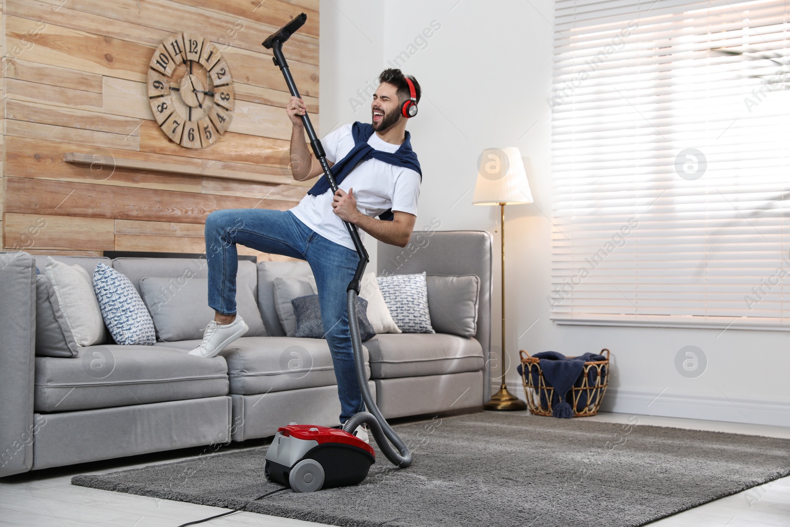 Photo of Young man having fun while vacuuming at home