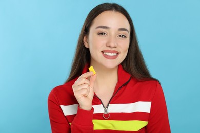 Happy young woman with bubble gum on light blue background