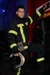 Photo of Firefighter in uniform closing door of fire truck at station