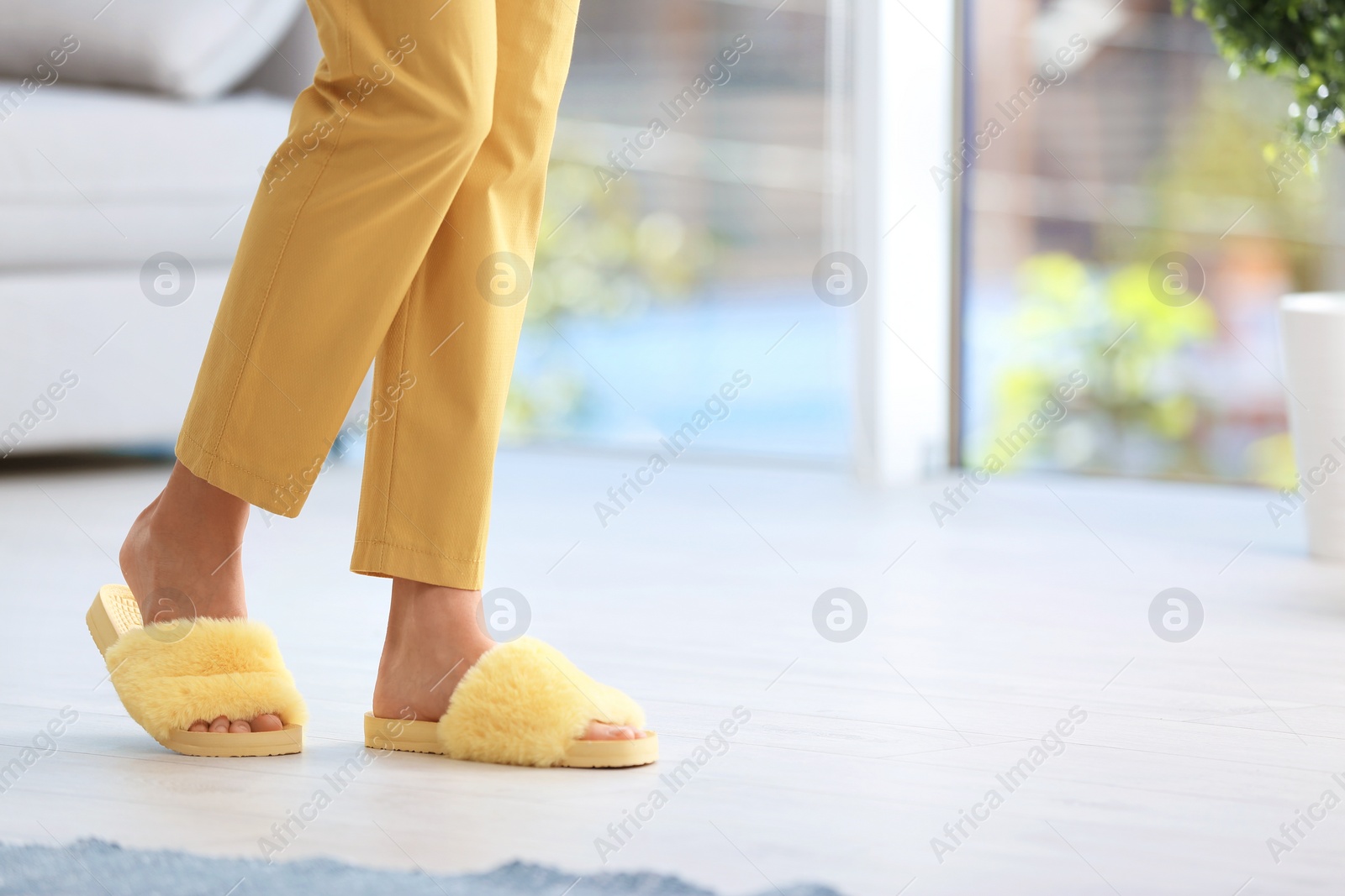 Photo of Woman in fuzzy slippers at home, space for text. Floor heating