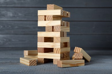 Photo of Jenga tower and wooden blocks on grey table. Board game