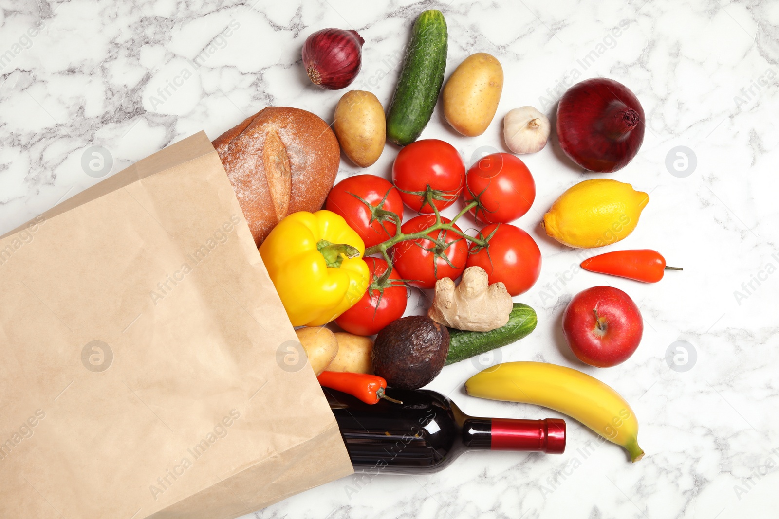 Photo of Shopping paper bag with different groceries on white marble background, flat lay