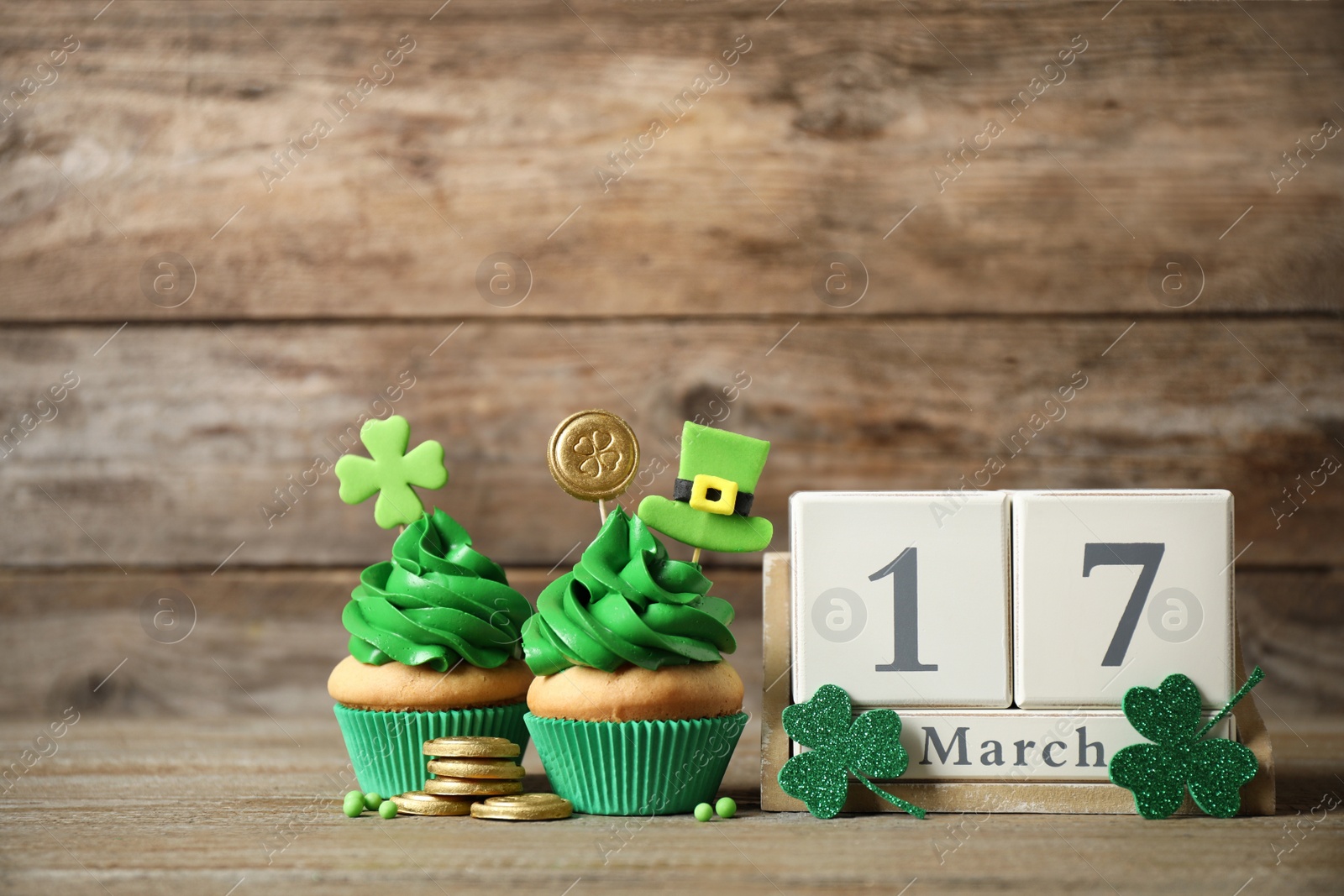 Photo of Decorated cupcakes, wooden block calendar and coins on table. St. Patrick's day celebration