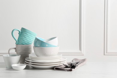 Photo of Beautiful ceramic dishware, cups and cutlery on white marble table, space for text