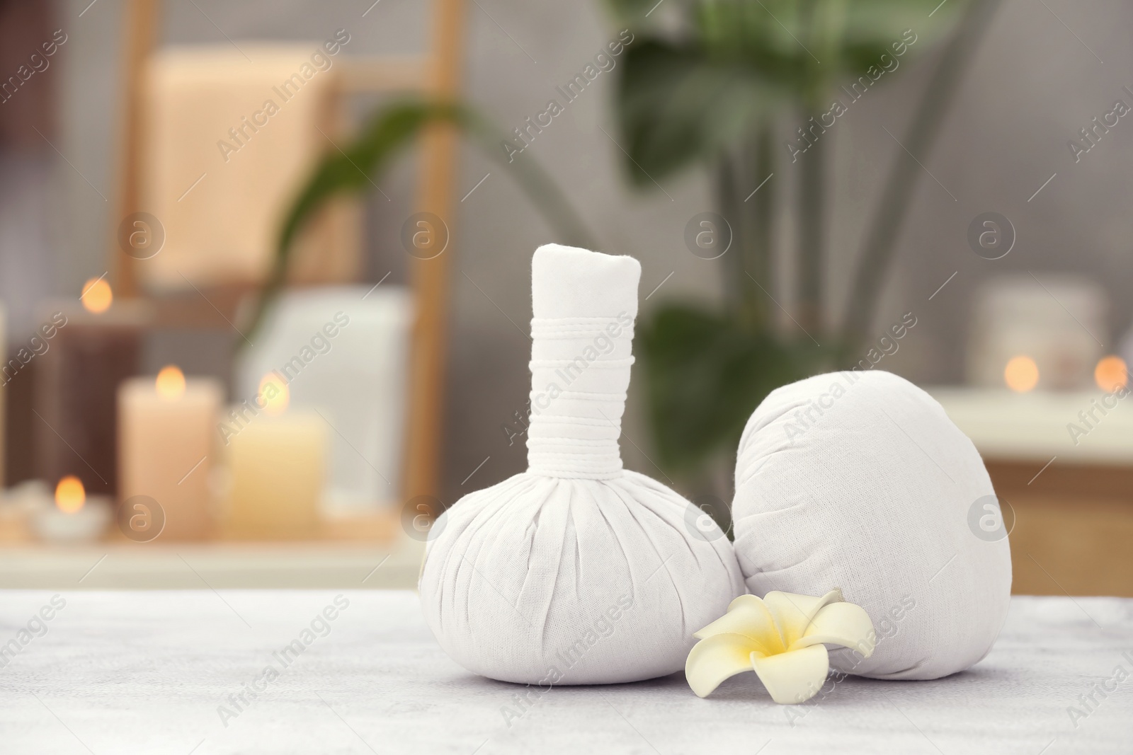 Photo of Beautiful spa composition with herbal massage bags and plumeria flower on light grey table in wellness center. Space for text