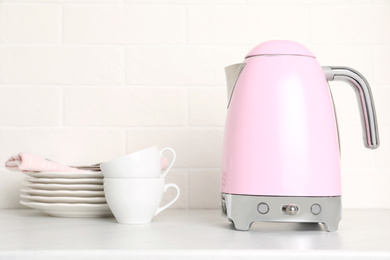 Photo of Modern electric kettle and dishes on counter in kitchen