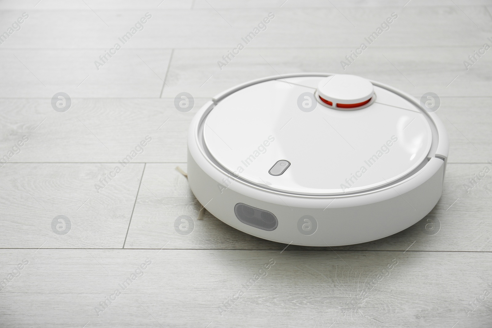 Photo of Hoovering floor with modern robotic vacuum cleaner indoors, closeup