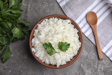 Photo of Bowl with tasty cooked rice on grey table, flat lay