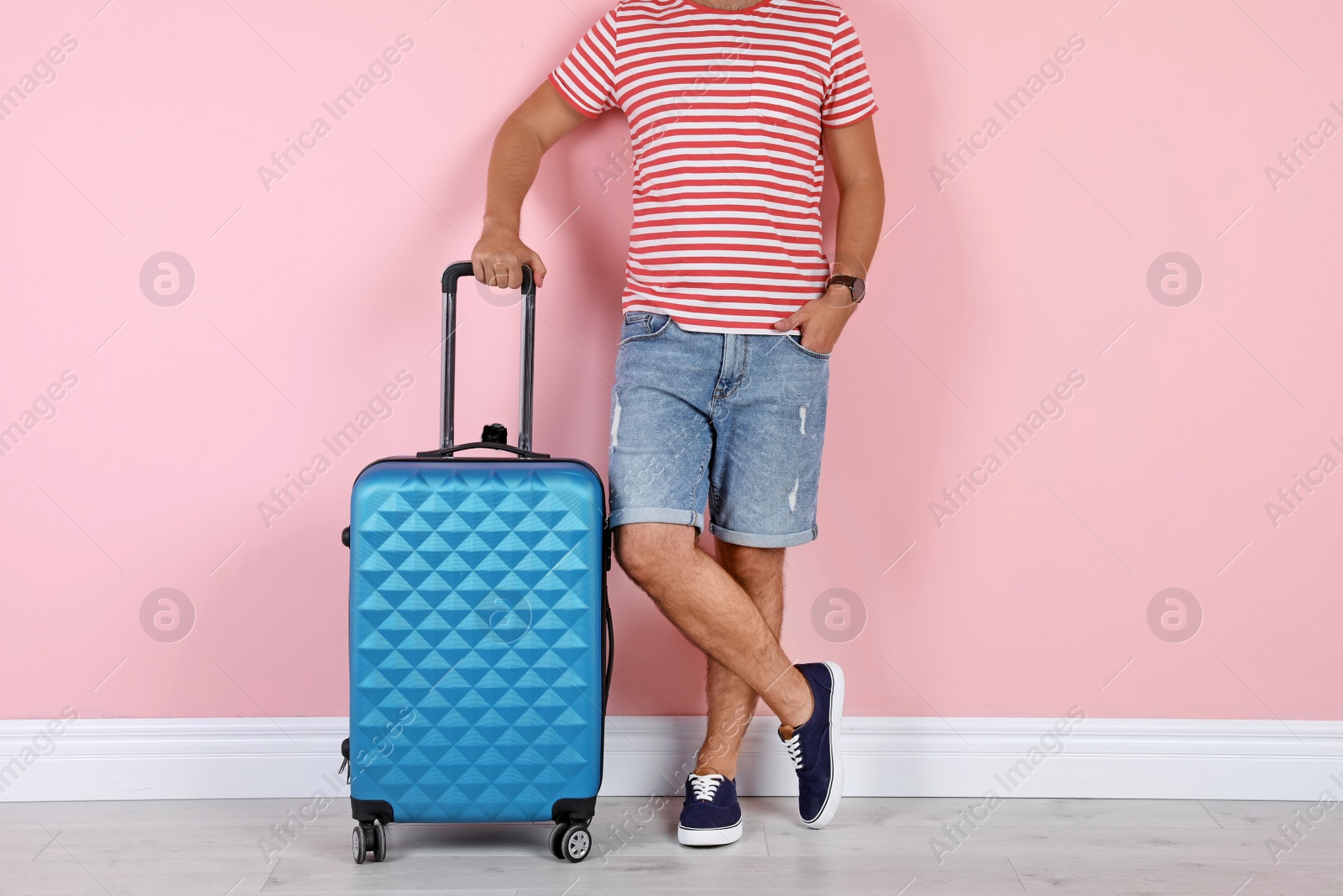 Photo of Man with suitcase near color wall. Vacation travel