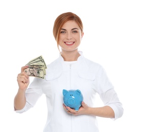 Portrait of female doctor with piggy bank and money on white background