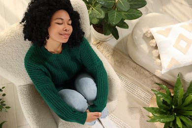 Photo of Woman relaxing near beautiful houseplants in room, above view