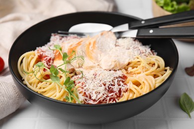 Delicious pasta with tomato sauce, chicken and parmesan cheese on white tiled table, closeup