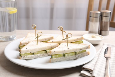 Tasty sandwiches with cream cheese and cucumber served on white wooden table