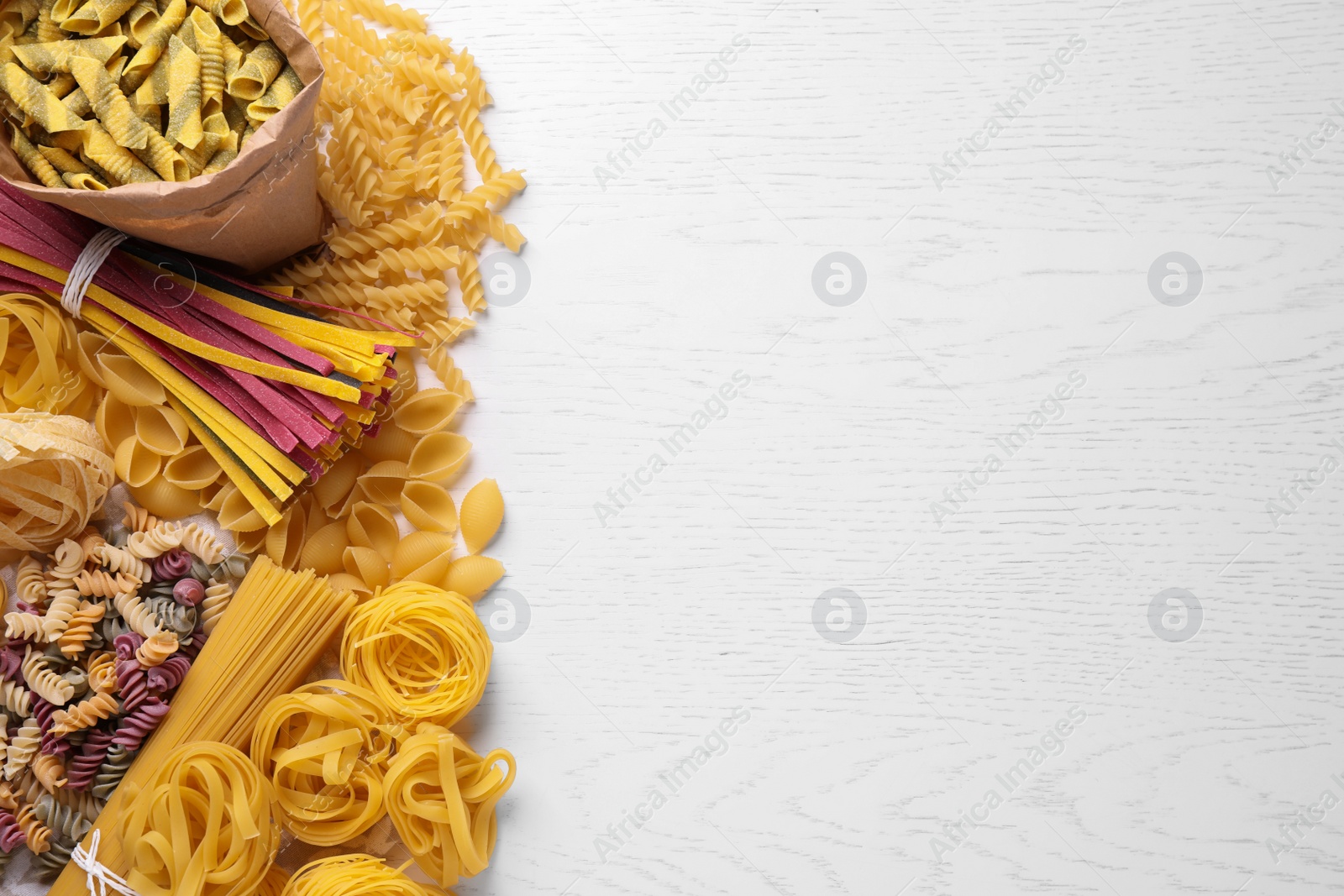 Photo of Different types of pasta on white wooden table, flat lay. Space for text